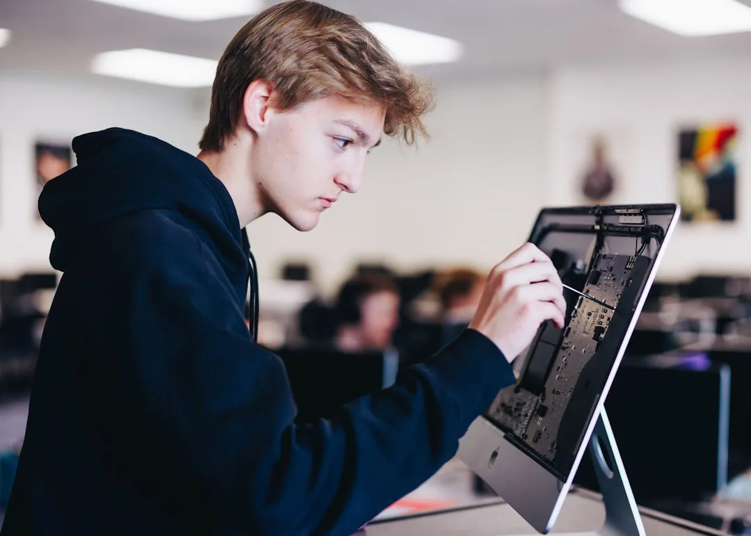 Teenage student in a hoodie working on a tablet mounted on a stand in a classroom