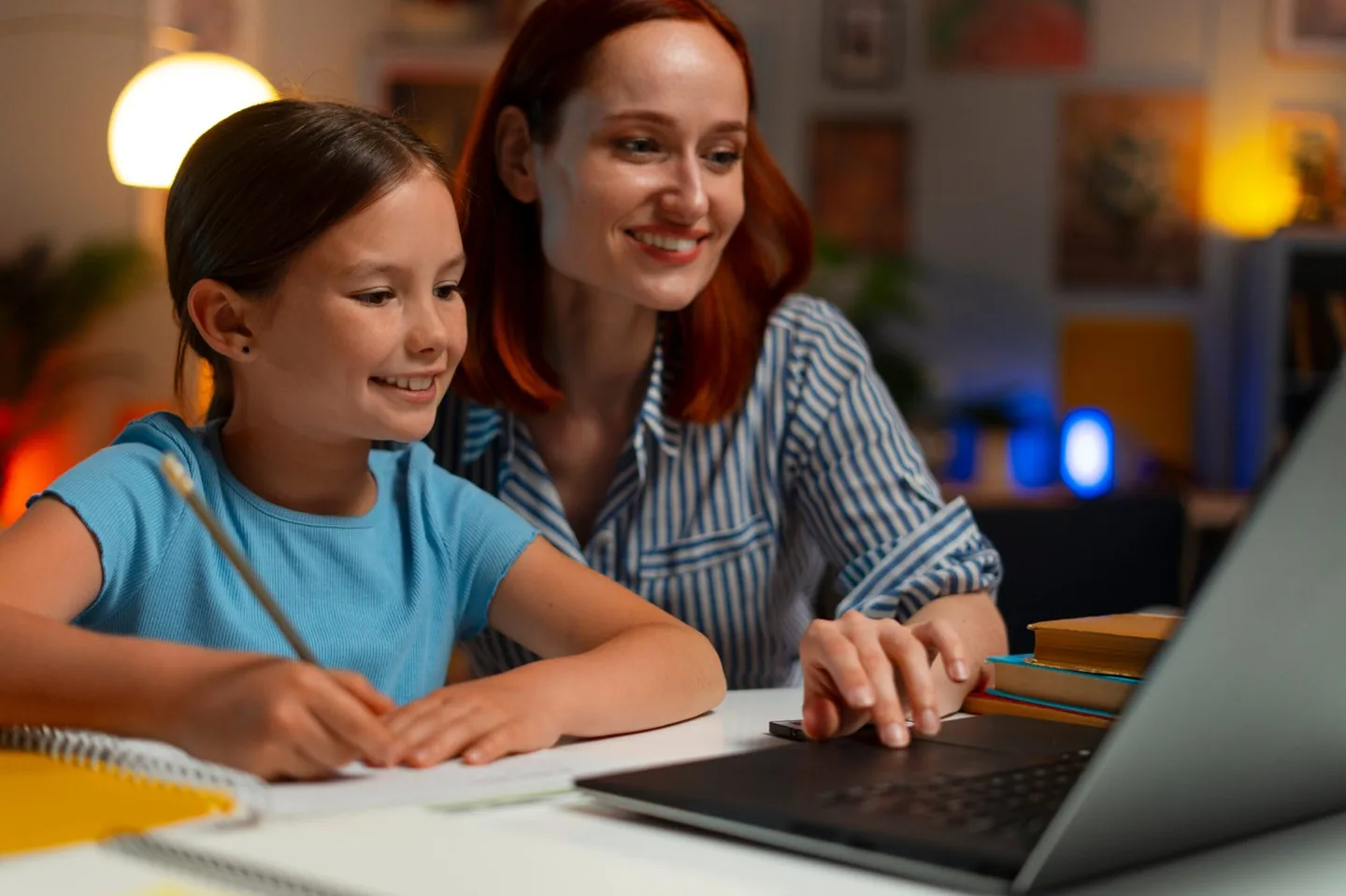 Parent helping her daughter with schoolwork at a laptop