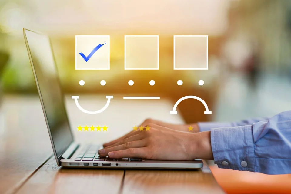 Hands typing on a laptop with rating check boxes and stars drawn above the keyboard