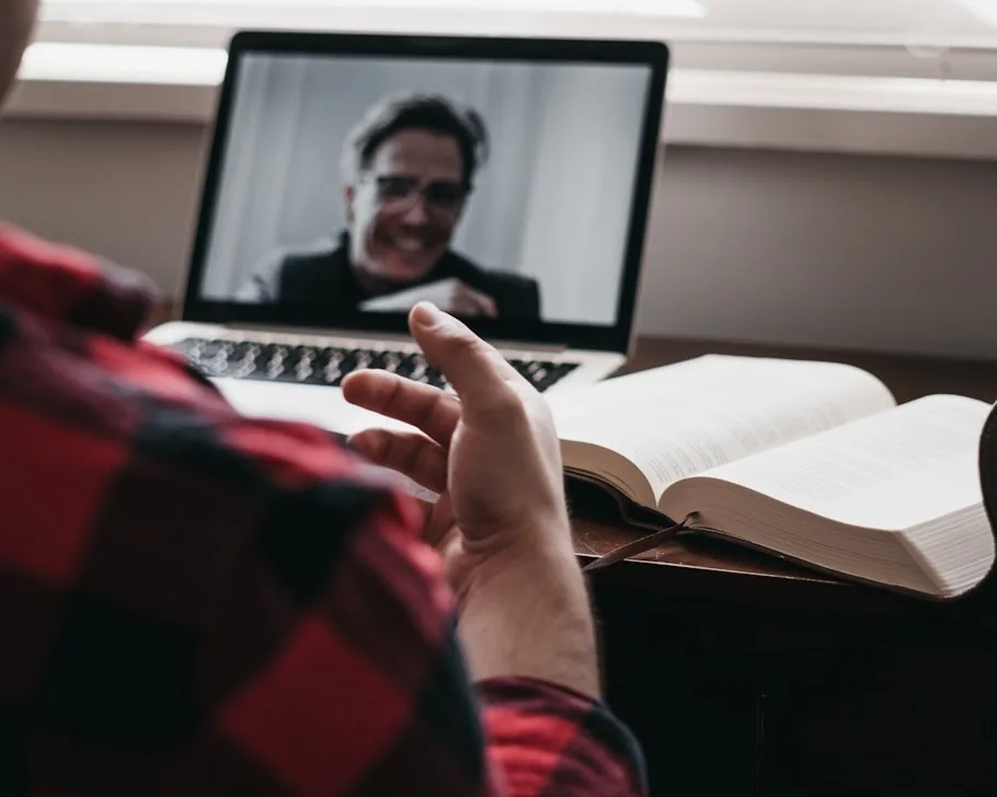 A tutor teaching a student over a video call on a laptop